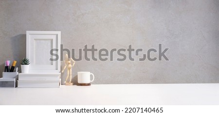 Minimal workplace with blank picture frame, books, coffee cup and cactus. Copy space for your text.