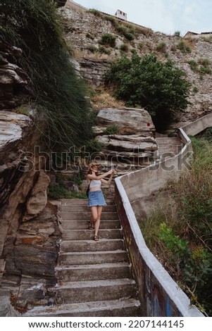 Woman traveler, walking on the stairs, taking pictures with smartphone, while exploring Greece mountains