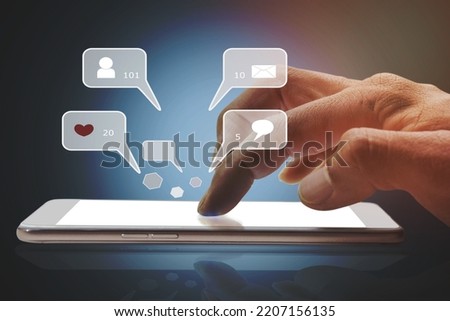 Closeup of person finger hand using a social media chat on a mobile phone with notification icons of like, message, comment, and star above smartphone screen.