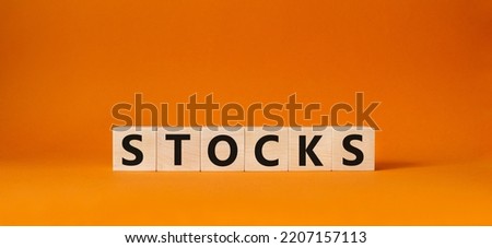 Stocks symbol. Concept word Stocks on wooden cubes. Beautiful orange background. Business and Stocks concept. Copy space.