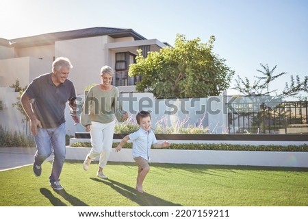 Family running, happy garden and child happy on grass with grandparents, smile for exercise in backyard and fitness together in nature. Grandmother and man playing with kid in park by house in summer Royalty-Free Stock Photo #2207159211
