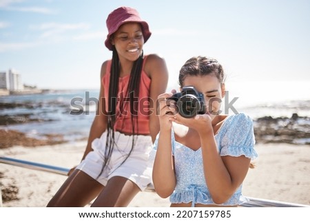 Summer, beach and photographer with camera, young girl taking a photograph. Friends, fun and happy teenagers on holiday by the sea with a scenic ocean view. Portrait of girls, photography and nature