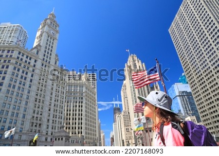 Tourist teenager admiring Chicago skyline on Michigan Avenue with American flag on the foreground in Chicago, USA