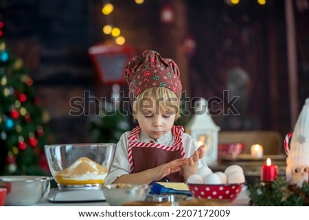 Cute blond child, toddler boy, baking christmas cookies at home, having fun