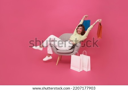 portrait of Happy Asian teen woman sitting on sofa with shopping bags isolated on pink background, Shopper or shopaholic concept. Royalty-Free Stock Photo #2207177903
