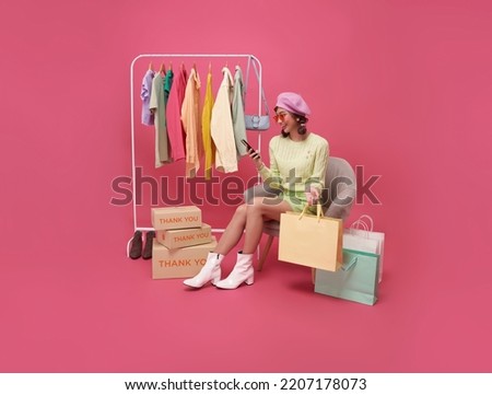 Happy Asian teen woman sitting on sofa holding shopping bags and smartphone isolated on pink background, Shopper or shopaholic concept. Royalty-Free Stock Photo #2207178073