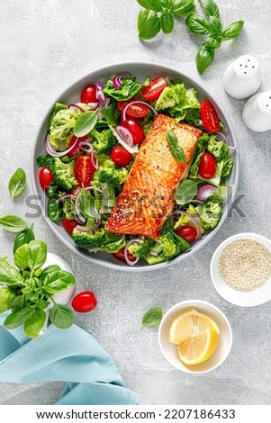 Grilled salmon fish fillet and fresh green leafy vegetable salad with tomatoes, red onion and broccoli. Healthy food. Ketogenic lunch. Top view Royalty-Free Stock Photo #2207186433