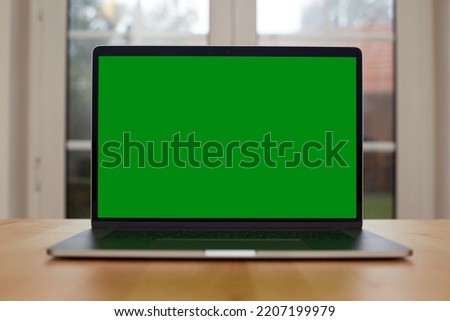 Laptop with blank screen on white table with mouse and smartphone. Home interior or office background. High quality photo