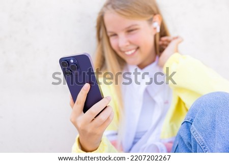 Teenage girl using mobile phone and listening to music on wireless earbuds