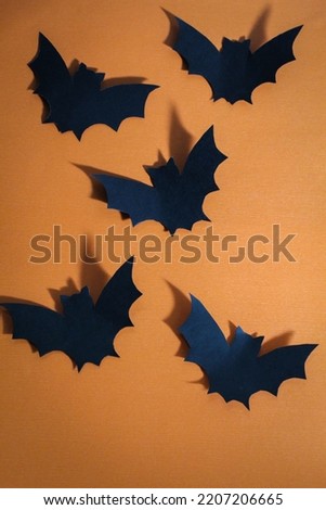 Five black bats on orange background as halloween background