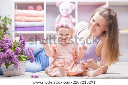 mother with a little daughter with a bouquet of lilacs in the children's room