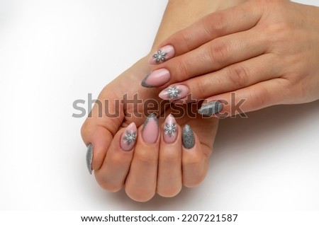 New Year's manicure with snowflakes. Silver manicure on long sharp nails dissolves on a white background.