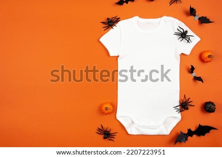 Halloween white baby girl or boy bodysuit mockup flat lay with pumpkins, spiders and bats on orange background. Design onesie template, print presentation mock up. Top view. 