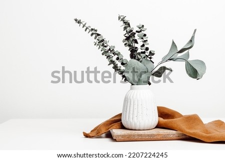 Vase with natural eucalyptus leaves on wooden stand with copy space, scandinavian interior style, home eco decoration