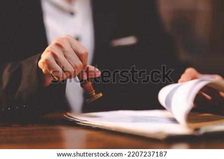 businesswoman person's hand stamping with approved stamp on certificate document public paper at desk, people work in notary law or business finance agreements, lawyer paperwork in confidential Royalty-Free Stock Photo #2207237187