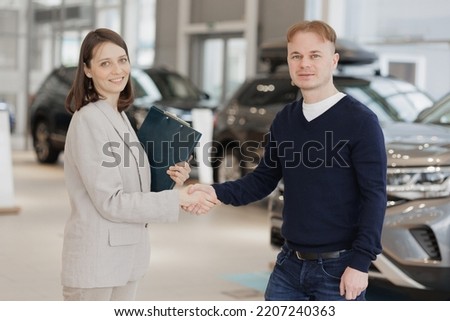 handshake, a man buys a car dealership and signs a contract. A successful man chooses a new car. Service center for rental or repair of vehicles. trade in loan secured by a automobile