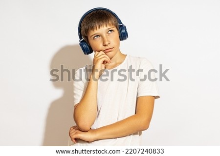 a boy in blue headphones listens thoughtfully to music.