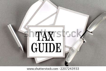 TAX GUIDE text written on sticky with pencil and glasses