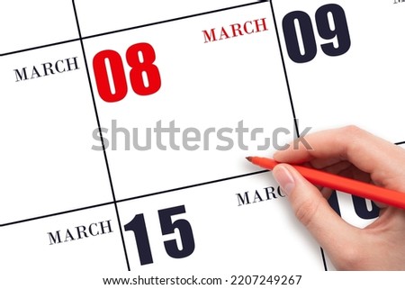 8th day of March. A hand holding a red pen and pointing on the calendar date March 8. Red calendar date, copy space, mockup. Spring month, day of the year concept.