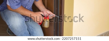 Picture of a handyman who with an oiler lubricates the hinges of a creaking door. Housework and do-it-yourself. Horizontal banner 