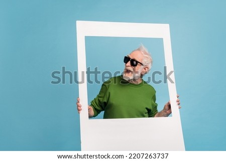 Portrait of crazy positive funky granddad hold album set card look empty space isolated on blue color background