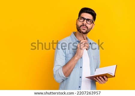 Photo of serious hispanic man write business report look empty space wear stylish jeans clothes specs isolated on yellow color background