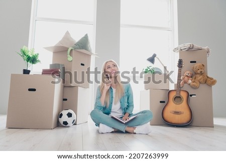 Photo of sweet pretty young lady dressed denim shirt writing packages list relocating new country indoors apartment