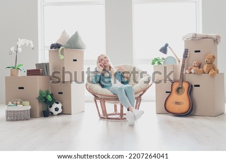 Photo of sweet dreamy young lady dressed denim shirt talking modern device discussing new flat indoors apartment