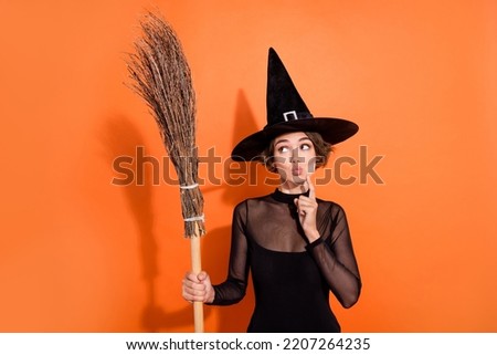Portrait of charming witch person finger touch chin pouted lips look empty space hold broom isolated on orange color background Royalty-Free Stock Photo #2207264235