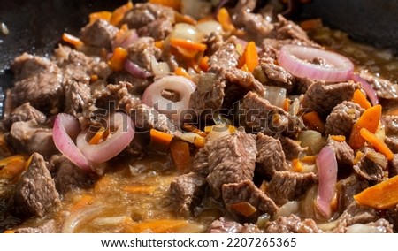 meat with vegetables in the process of cooking in a pan