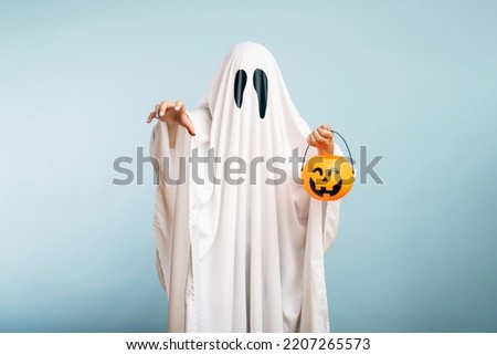 A white ghost with black eyes, made from a bedsheet with pumpkin basket
