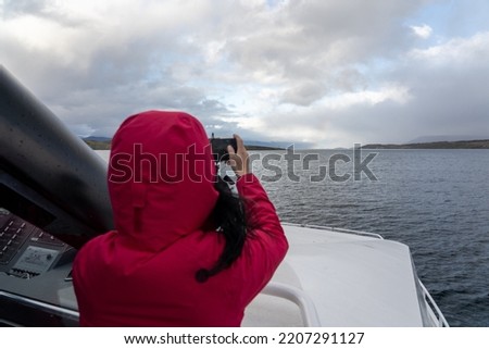 woman taking a picture during a vacation trip saling throught the beagle channel in winter