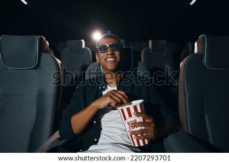 african american man in 3d glasses eating popcorn and watching film in cinema. High quality photo