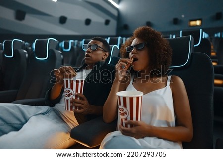 A couple with popcorn in an empty cinema watching a movie. High quality photo