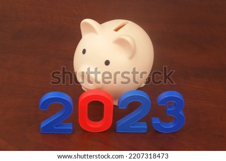 Piggy bank and numbers 2023 on wooden table, saving money and budget in 2023 concept.