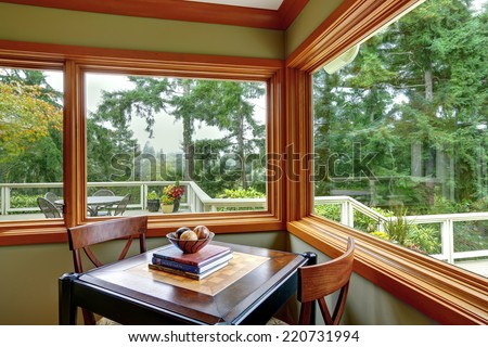 Corner with green walls and brown trim. Furnished with dining table with two chairs