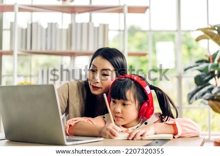 Mother and asian kid little girl learn and look at laptop computer reviewing lesson study with online education e-learning.student look for educational knowledge in homeschool at home.Education