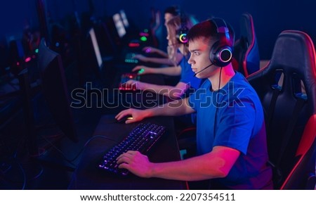 Cybersport team concept. Portrait young man pro gamer with headphones playing in online video game in tournament, neon color, soft focus.