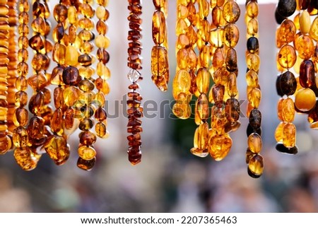 Warm gold colored amber jewelry necklaces on display at Mariacka street in Gdansk. Cose up picture of amber jewelry. Royalty-Free Stock Photo #2207365463