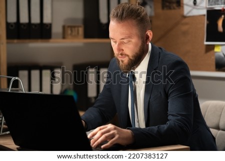Detective processing evidence in office using computer working at desk in his office at night. Copy space
