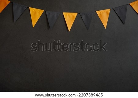 Halloween garland of black and orange flags on a dark background with space for text
