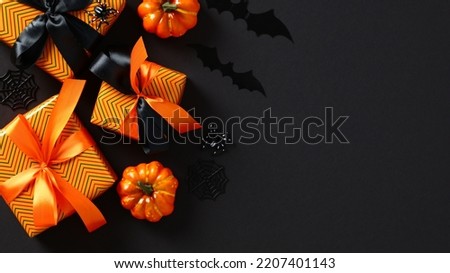Halloween gift boxes, pumpkins, spiders, bats on black background. Halloween sale, special offer, promotion, discount banner. Flat lay, top view, copy space.