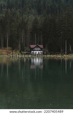 Small hut in the Italian Dolomites with a green forest in the back. Moddy evening with wiew on the lake Dobbiaco, South Tyrol, Italy, Europe. 