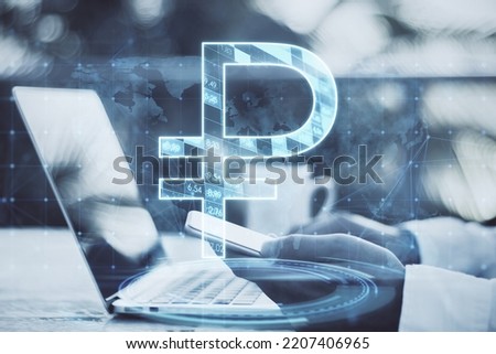 Close up of businessman hands using laptop and smartphone with glowing ruble and map hologram on blurry background. Money, currency, trade, online banking and app concept. Double exposure