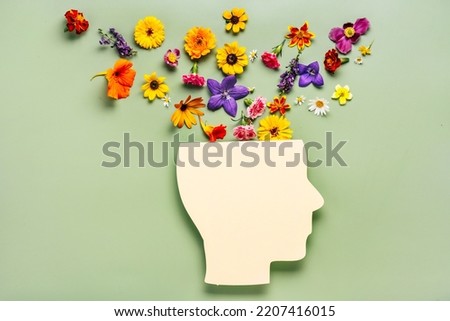 Mental health concept. Paper cut human head symbol and flowers on a green background