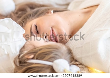 Mom and daughter play lying on the bed in the bedroom.Family. Ethno-interior design.