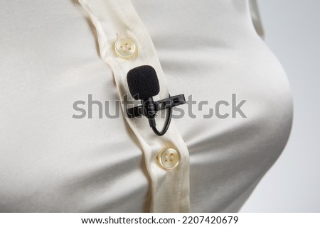small microphone on a clothespin for voice recording is attached to a woman shirt on the chest