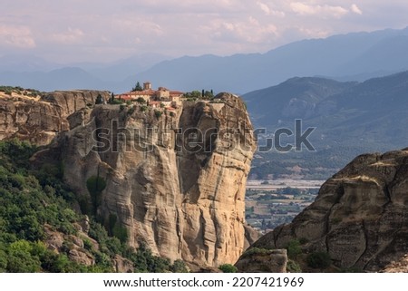 Panoramic photo of northwestern side of St Stephen Monastery with church built in 1798 and spacious plain with trees and mountains with gentle tones, Meteora, Greece
