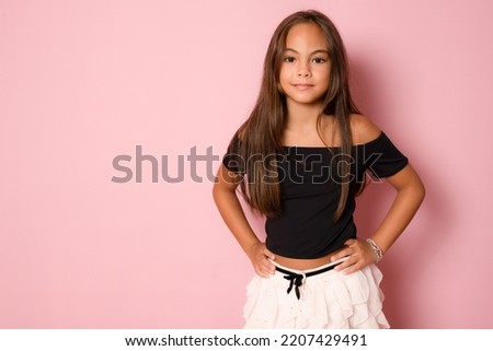 Portrait of pretty cut child girl smiling standing isolated over pink background.