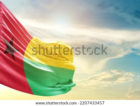 Guinea-Bissau national flag waving in beautiful sky.